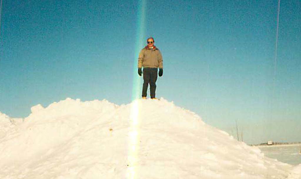 A man stands on a pile of snow.