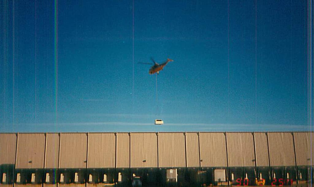 Helicopter lifting HVAC unit over distribution center