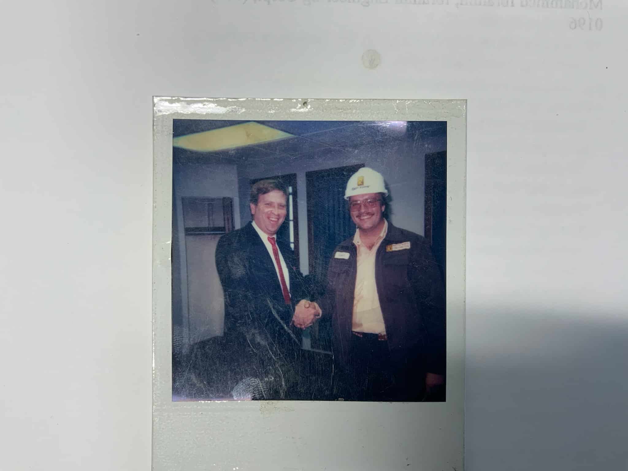 polaroid of man in suit and man in hardhat shaking hands
