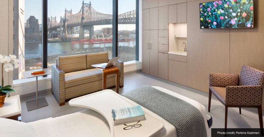 A patient room with a large picture window overlooking a waterfront.