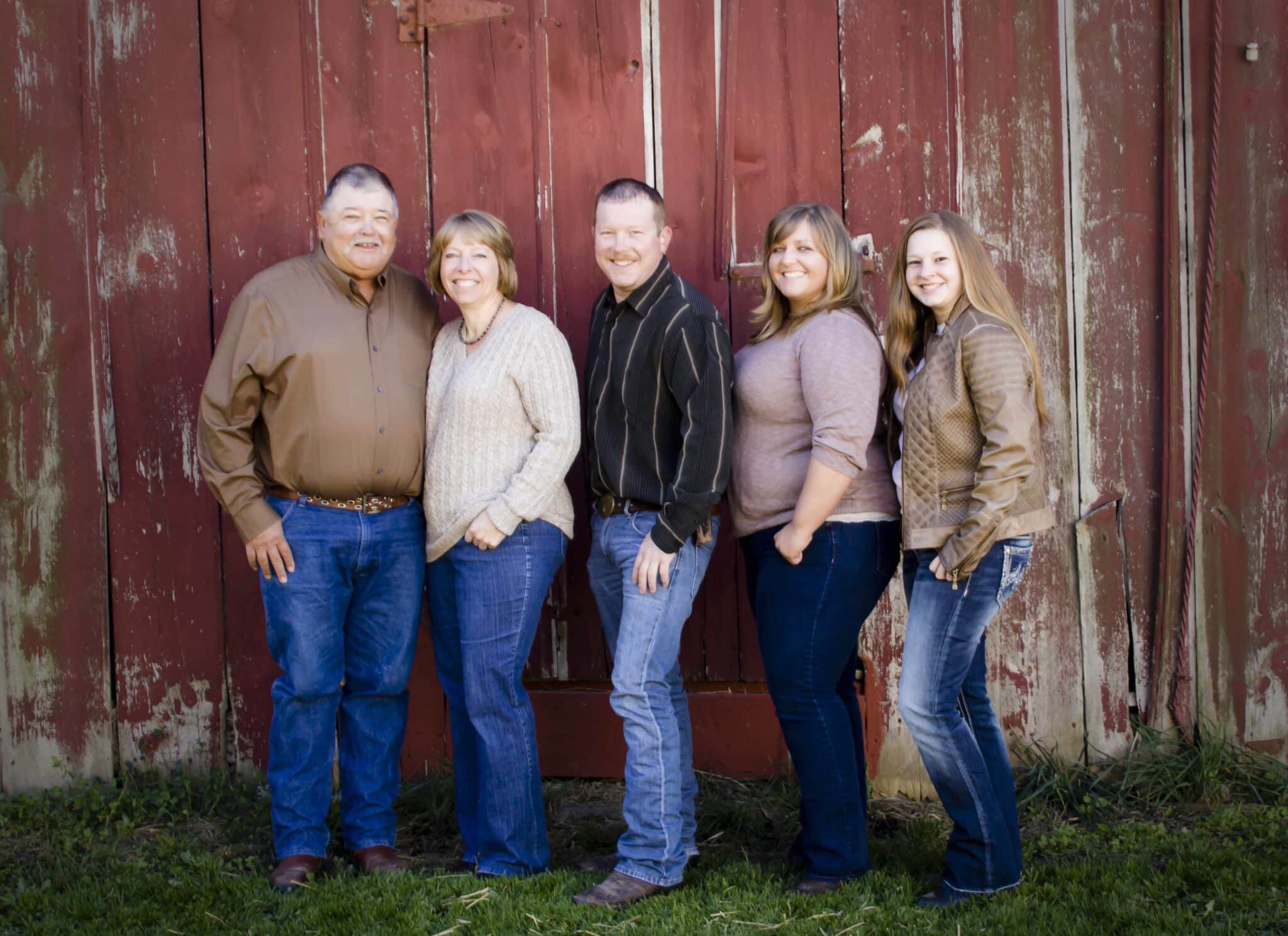 Family portrait of parents with adult children in front of barn