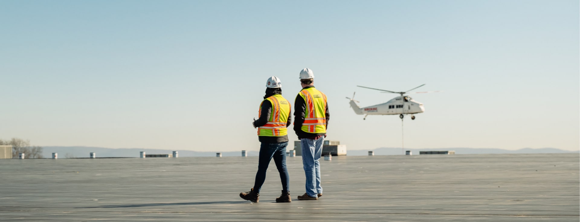 Korte employees on roof of warehouse with helicopter in the background