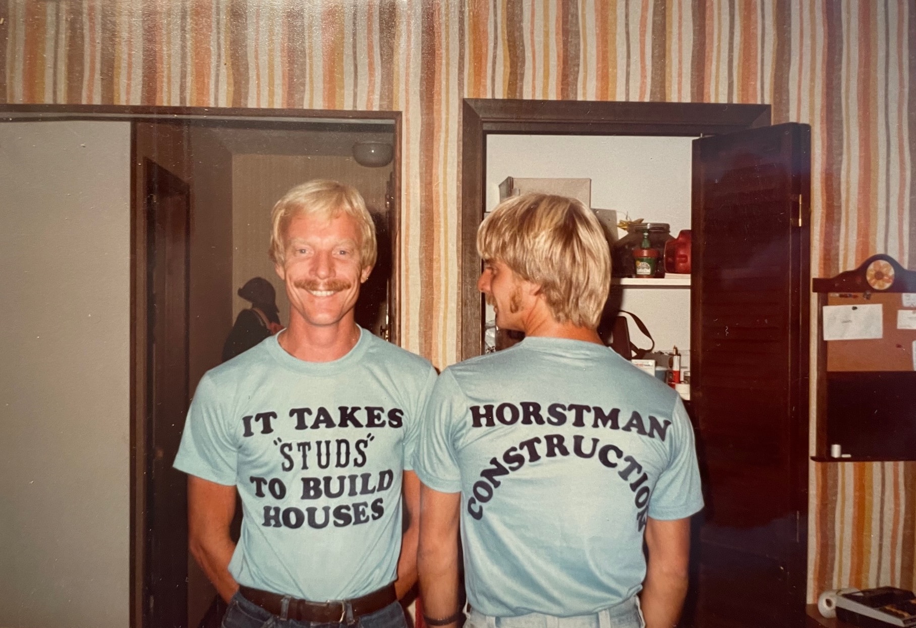1970s image of two blonde men (the Horstmann brothers) wearing Horstmann Construction t-shirts.