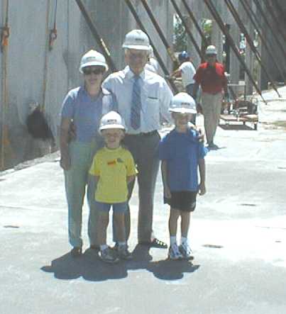 Ralph Korte and Susan Bowman posing with grandchildren on a construction site. All are wearing hardhats.
