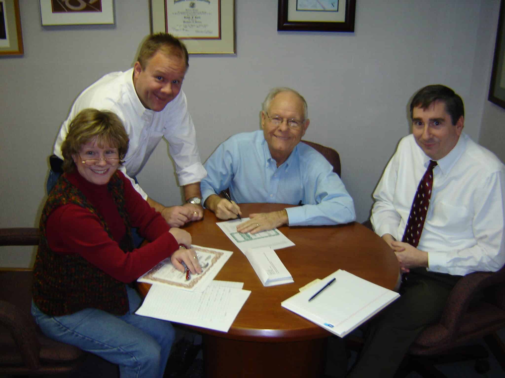 Ralph Korte signing the contract to turn The Korte Company over to his children. Susan Bowman is on left with two brothers.
