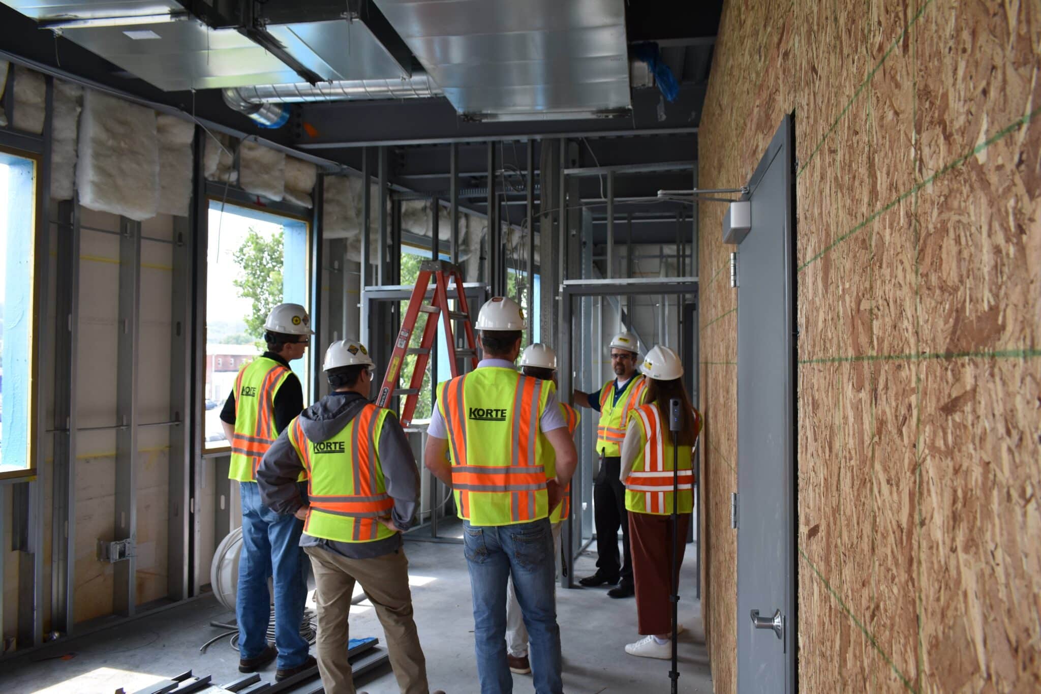 Group of Korte interns in yellow safety vests and hard hats at an indoor job site.