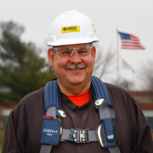 Man with fall safety gear and hard hat smiling at camera