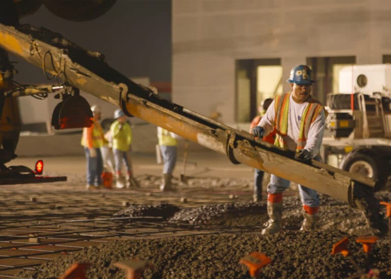 Worker holding spout pouring conrete