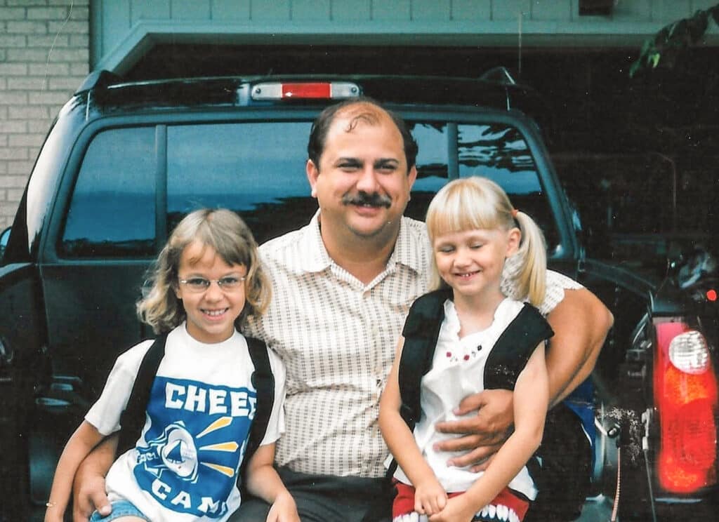 Brian sits on a tailgate with his daughters.