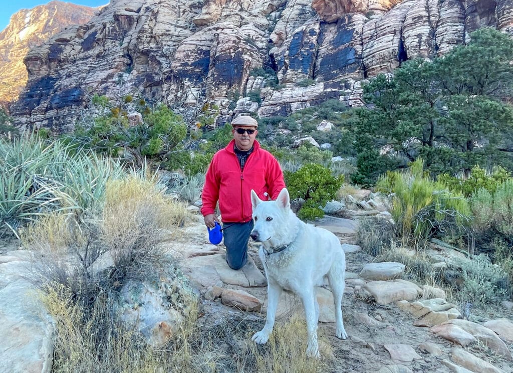 Brian Taylor walks with his dog through a mountainous landscape.
