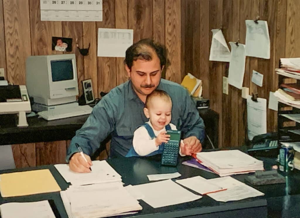 Brian works at his desk with a baby on his lap.